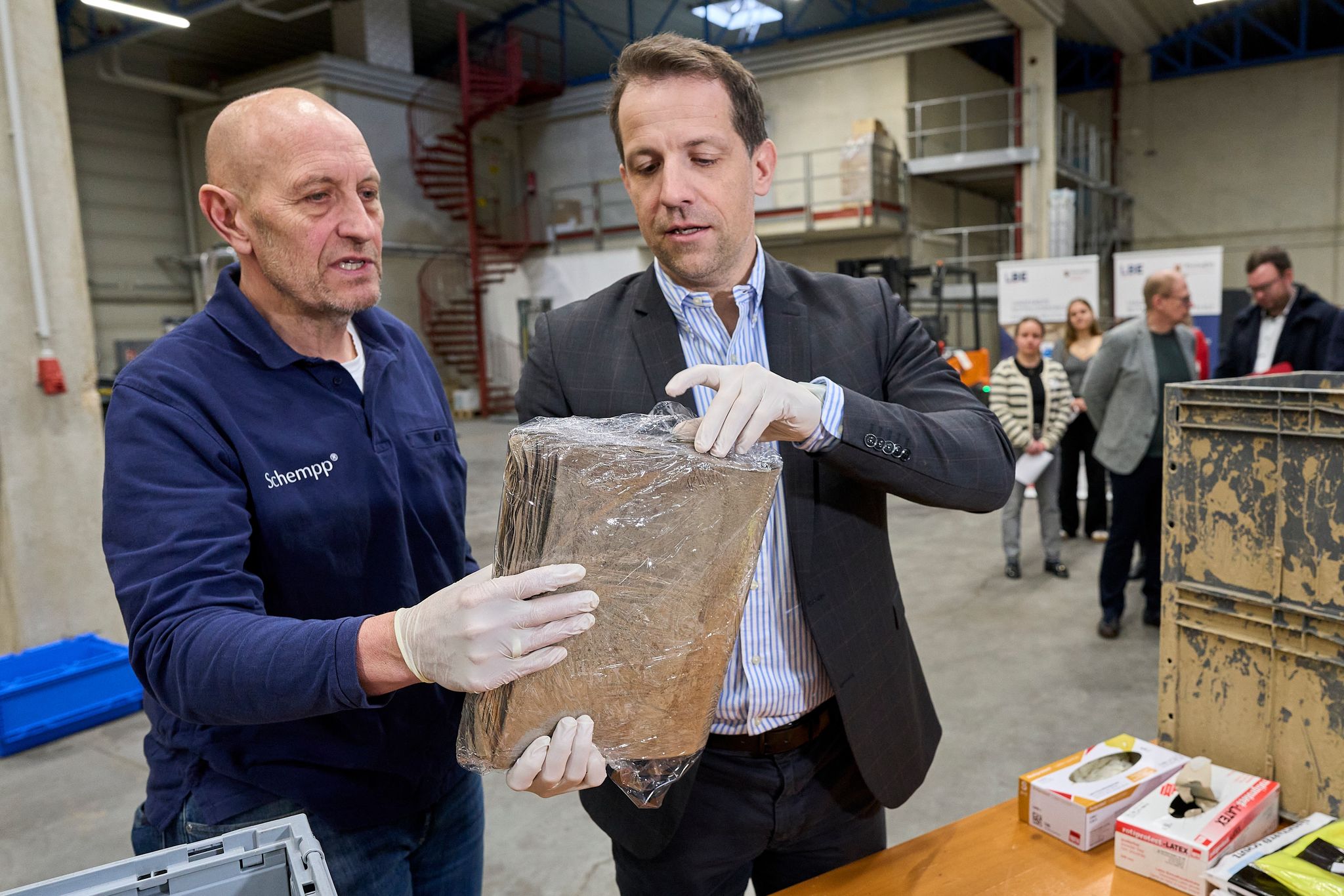 Der Experte Norbert Schempp (links) und der Mainzer Oberbürgermeister Nino Haase (parteilos) verpacken einen im Ahrtal geretteten Ordner in Stretchfolie. 