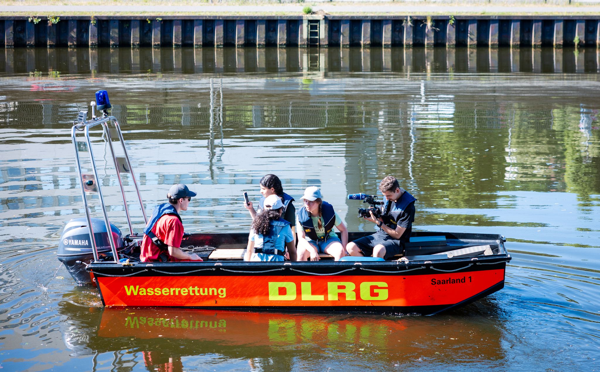 Schülerinnen und Schüler aus Saarbrücken sitzen in einem Rettungsboot der DLRG auf der Saar.