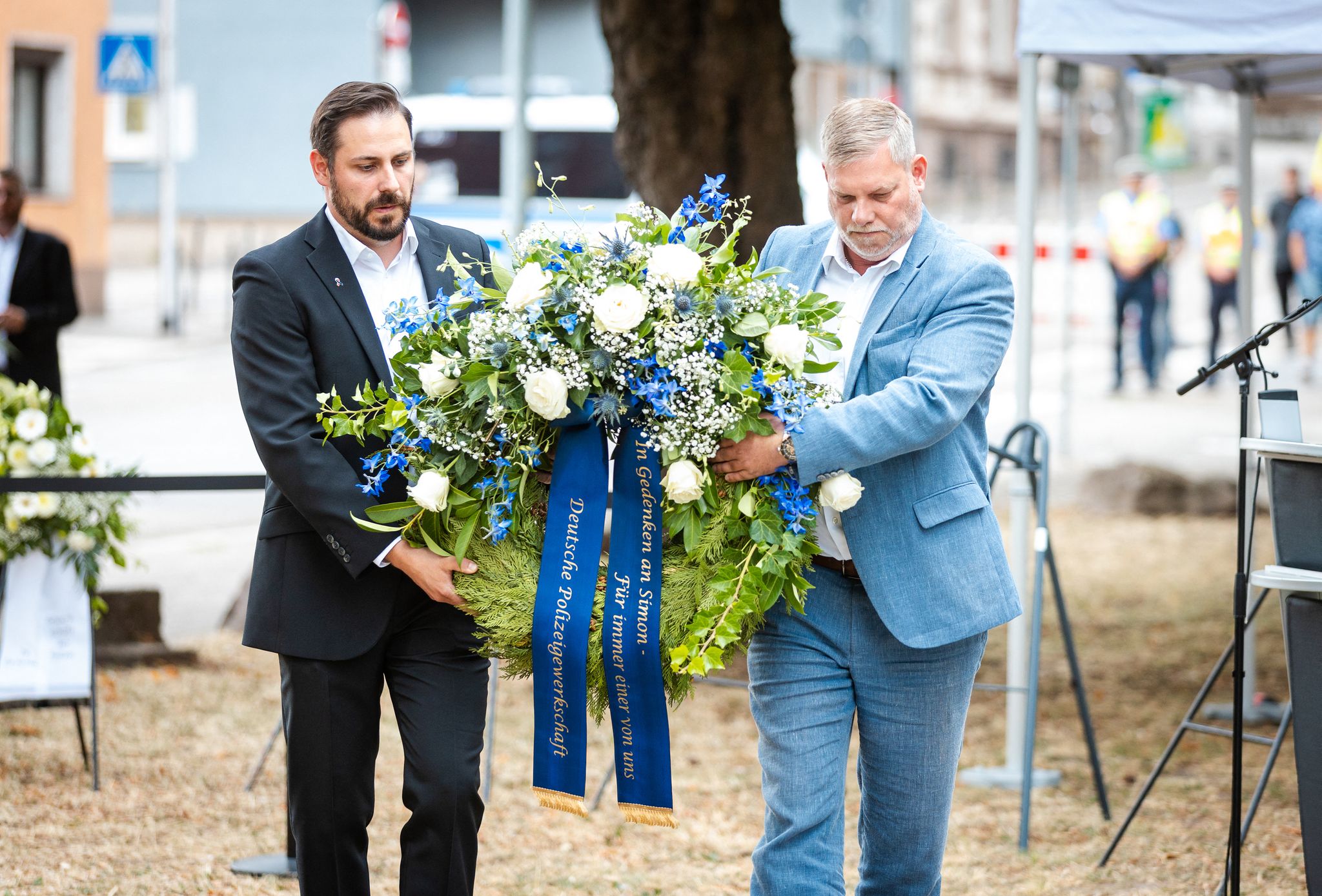 Markus Sehn (l.), Landesvorsitzender der Deutschen Polizeigewerkschaft (DPolG) Saarland, legt gemeinsam mit einem Kollegen einen Kranz an der Gedenkstele für den getöteten Polizeioberkommissar Simon Bohr nieder.