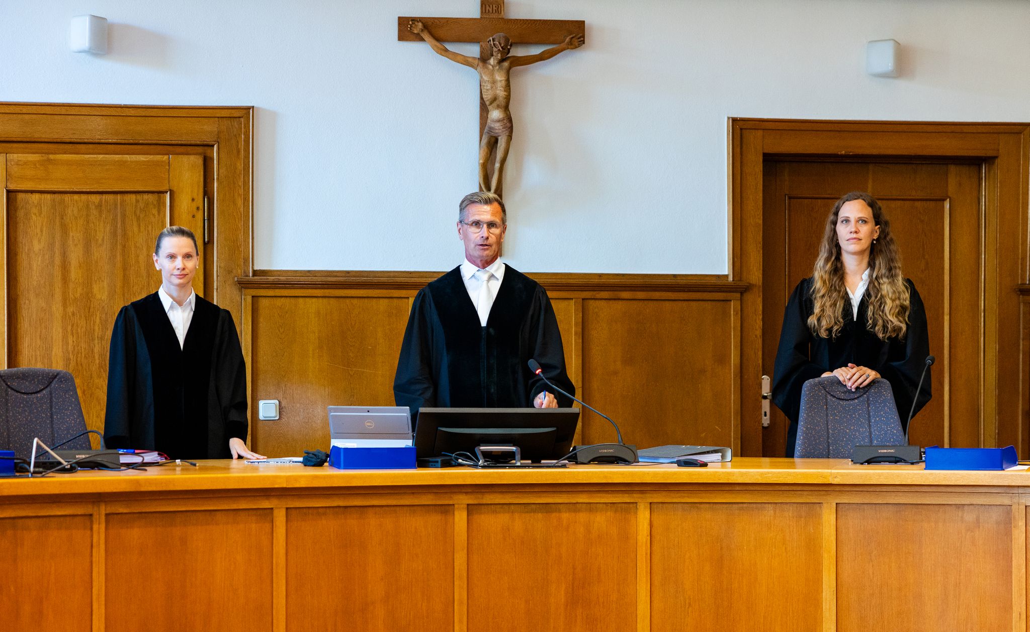 Der Vorsitzende Richter Klos (M) steht mit den Beisitzerinnen Hennersdorf und Christian auf der Richterbank im Saal 137 des Landgerichts.